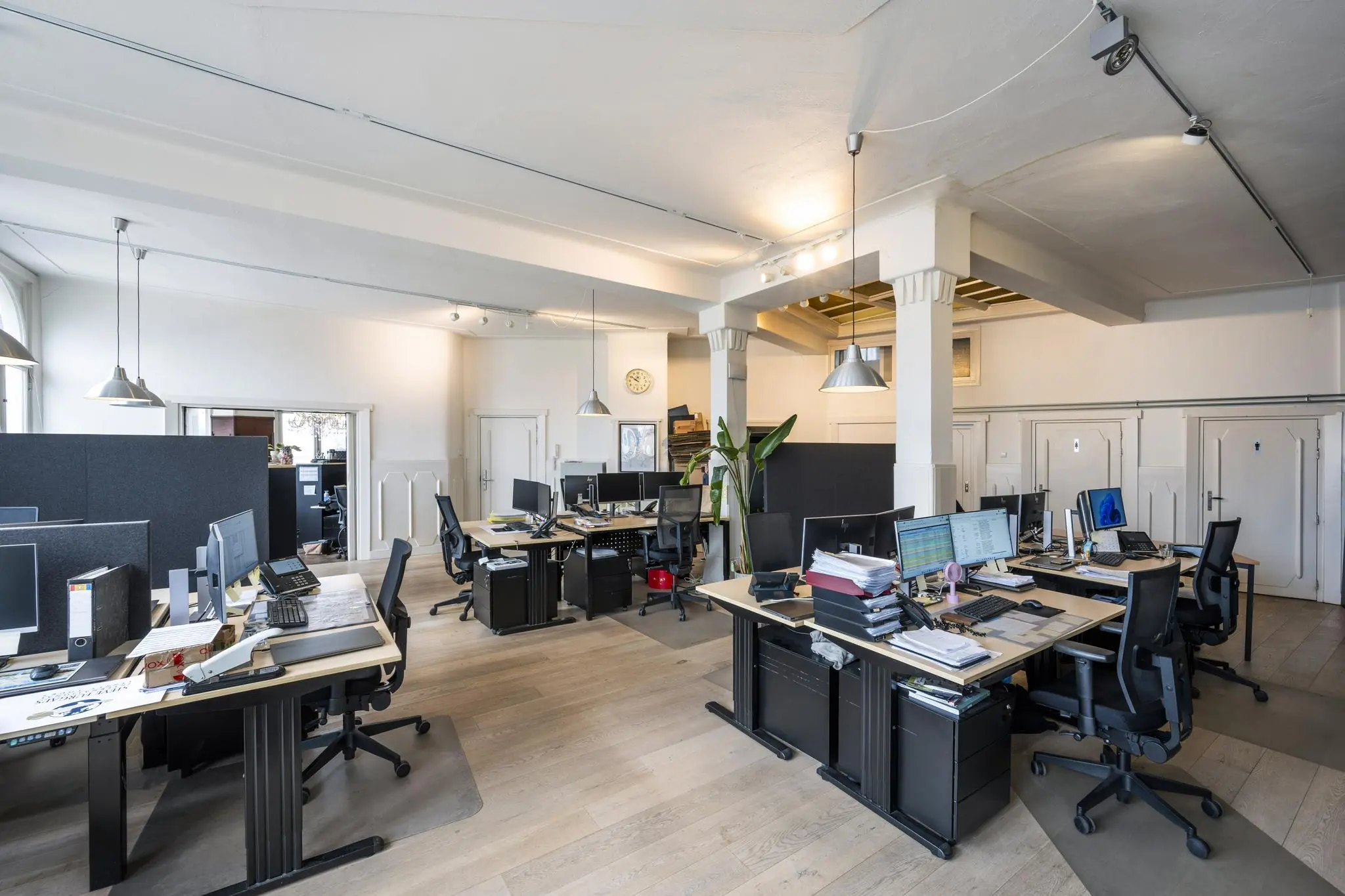 Ruim en licht kantoorinterieur aan de De Ruijterkade met meerdere werkplekken, computers en moderne inrichting.